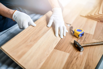 Man installing laminated wooden floor, Professional floor work in new house.