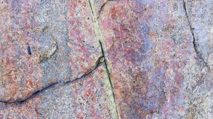 Texture of granite. Granite rock with reddish color. Background from solid stone. Pattern with natural material. Widescreen