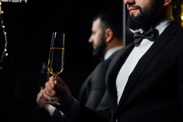 Successful handsome man in classic suit holds a glass of champagne. Bearded man in classic suit having luxury style. Merry Christmas and a happy new year 2020. Reflected in the mirror