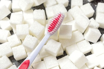 toothbrush on the background of the sugar cubes of refined sugar, preventing tooth decay, caring for the health of your teeth, the causes of caries