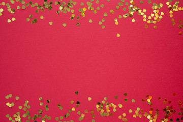Valentine's Day abstract red background with golden heart shaped glitter. Party or Valentine's Day flat lay. Greeting card. Copy space.