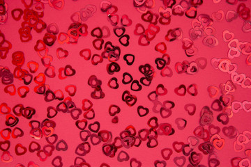 Valentine's Day abstract red background with red heart shaped glitter. Party or Valentine's Day flat lay. Greeting card.