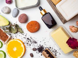 Fototapeta na wymiar Self care products from natural organic ingredients. Modern medicine, apothecary. Butters, soap, serum, scrub, orange slices, avocado, stones for massage Flat lay style.