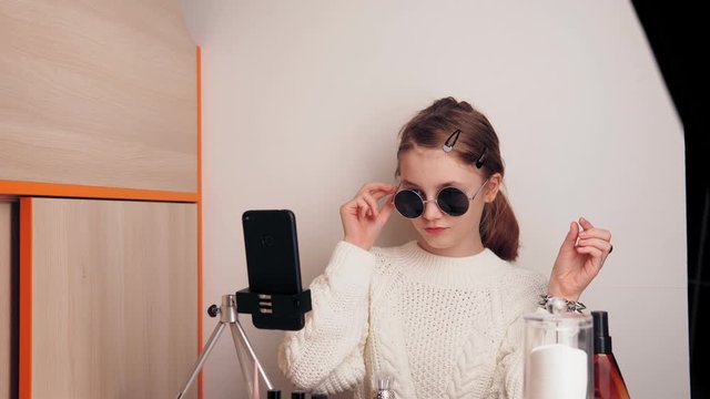 Stylish young girl blogger records video for a blog on social networks using a smartphone camera on a tripod.