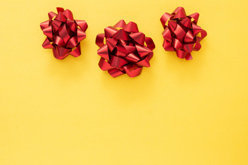 Red ribbon bows over colorful yellow background. Birthday, Christmas or Valentine's day mock up frame or border.
