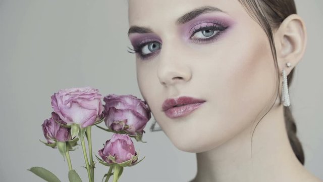 Young girl with pink make-up and with pink roses. Natural cosmetic. Clean face skin. Pink lip gloss. Woman with roses. Valentines Day.