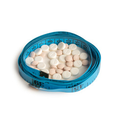 blister with tablets and tied with measuring tape, the concept of taking drugs for weight loss and maintain the figure, the harm of supplements for weight loss, isolated on white background