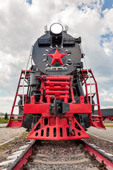 vintage steam train on the rails close-up on blue sky background, retro vehicle, steam engine, front view