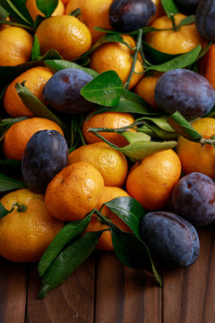 fresh mandarines and plums on wooden background