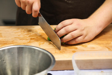 Fototapeta na wymiar Cutting greens with knife in professional kitchen