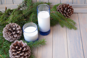 Christmas time, two blue glass of milk with pine branch and cones on blue wooden table, copy space