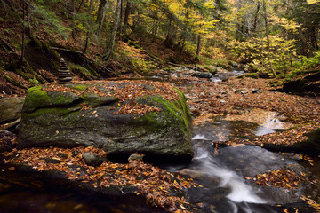 Stacked rocks at Sterling Brook below the Falls with boulders and Fall foliage north of Stowe Vermont