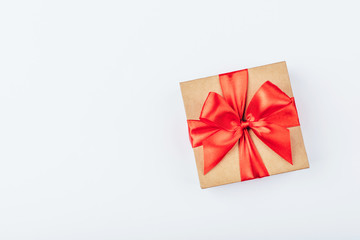 Cardboard gift box with red bow on white background. Flat lay. Top view. Copy space for your text.