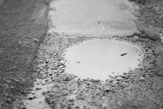 puddle on a wet asphalt road, bw photo.