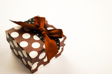 Christmas present with a bow lies on a white table. A small gift on a white background. Merry Christmas