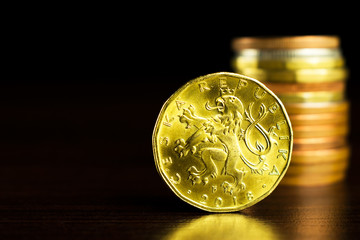 Businessman holds a yellow coin with his finger. Czech korunas on the table. Yellow coins on the...
