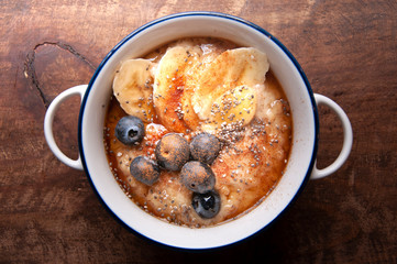 Porridge breakfast with banana, blueberry, oatmeal, chia, cinnamon. Top view with top view.