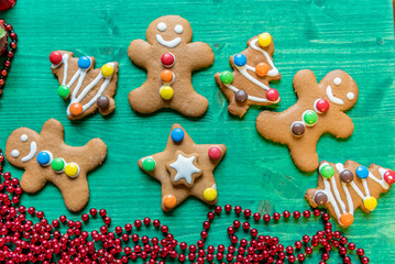 Colorful, decorated, gingerbread cookies, Christmas edition with red pearls, festive, on green wooden background  