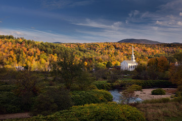 Obraz premium Stowe Community Church and Brush Hill with Fall colors in evening sun at Stowe Vermont