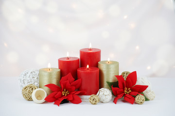 Red and gold Christmas candles surrounded by red poinsettia flowers, gold twig balls and natural...