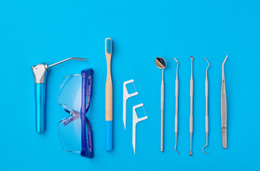 Dentist tools over blue background top view copy space flat lay. Tooth care, dental hygiene and health concept.