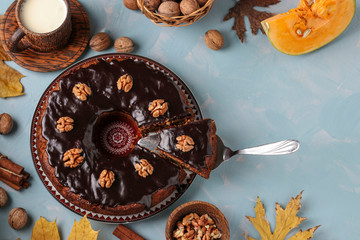 Homemade pumpkin muffin, with a cut out slice, decorated with chocolate icing and walnuts on a light blue background, Copy space, horizontal orientation