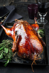 Traditional roasted stuffed Christmas Peking duck with herbs as closeup on a board