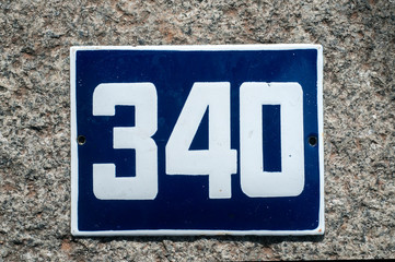 Weathered grunge square metal enameled plate of number of street address with number 340 closeup