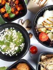 Culinary dishes made from natural products in a plastic bowl on the background with ingredients for cooking. Healthy food delivery concept. Top view.