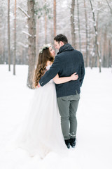 winter wedding in the forest, bride and groom embracing, standing and looking each other