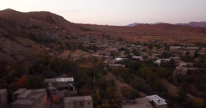 An aerial shot from a village in autumn leaves colorful trees forest and stair shape village town in mountain landscape in Iran