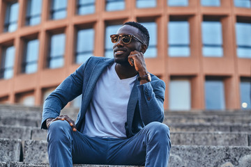 Young attractive student is sitting on the stairs in the middle of city centre.