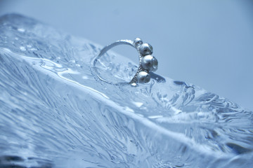 Close-up silver ring frozen into a piece of ice, photo on a white background, selective focus