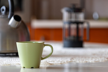 Coffee cup and metal kettle on the kitchen table. Morning coffee in the home kitchen.
