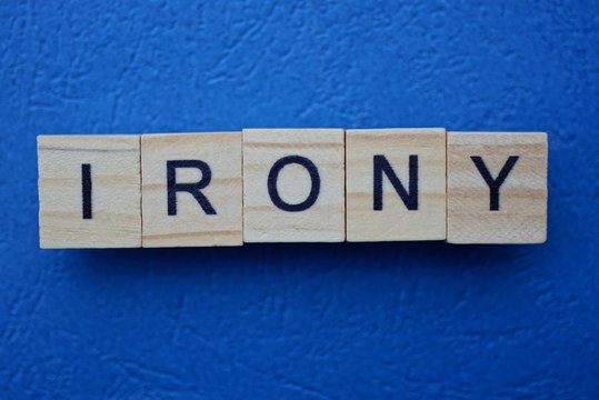 Naklejki word irony made from wooden letters lies on a blue table