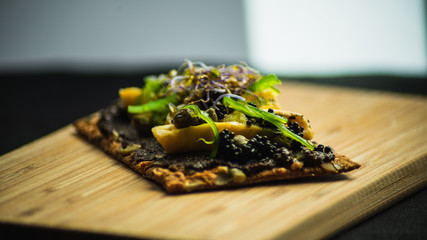Tostada de tortilla con olivada y algas sobre tabla de madera