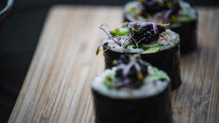 Sushi cortado sobre tabla de madera y palillos