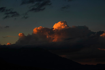 dark sky with orange storm clouds over mountain range