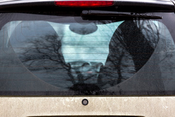 rear wagon trunk lid of a dirty car in the mud after an off-road trip, close-up of a back window...
