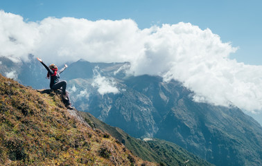 Young hiker backpacker female rising her arms,cheerful laughing and enjoying valley during high altitude Everest Base Camp (EBC) trekking route near Namche Bazaar,Nepal. Active vacations concept image