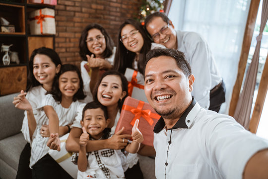 asian family wearing white take selfie using smartphone together at home on christmas day