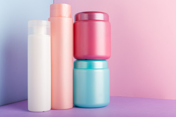 Set of cosmetic products on pink background. Cosmetic package collection for shampoo, mask, conditioner, shower gel. Pink, white, blue plastic bottles, jar for packaging cosmetics Mock up, copy space