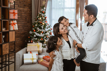 asian family with two children in livingroom with christmas tree