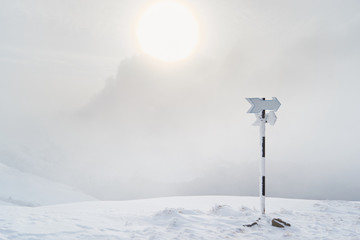 Blank hiking trail arrow/marker during a whiteout blizzard in the Carpathians (Baiului mountains), Romania, in Winter. - obrazy, fototapety, plakaty