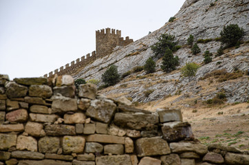 Old fortress in the mountains, a wall and towers on a cliff.