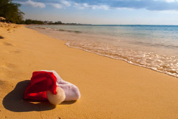 A tropical Christmas image. Santa's hat lies on a sun drenched beach in the Caribbean while he thaws out in the warmth.