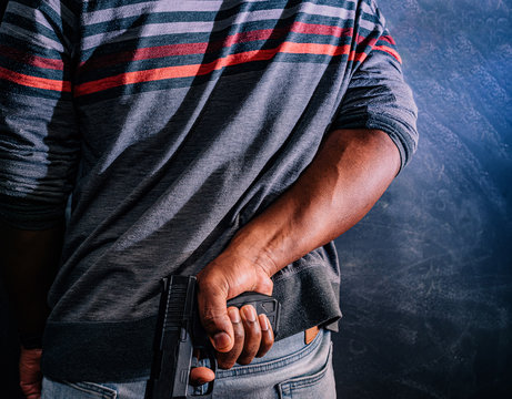 conceal carry concept african american male with handgun behind back