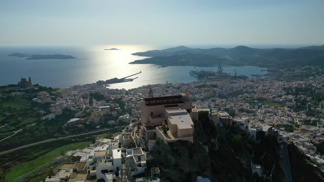 Aerial drone video of iconic uphill catholic settlement of ano Syra featuring church of Saint George at sunset with beautiful colours, Syros or Siros island, Cyclades, Greece