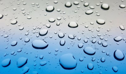 Splashes of raindrops on a car windshield after a storm. Angled point of view for depth of field and selective focus.