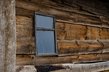 A small window in the wall of an old wooden shed.
